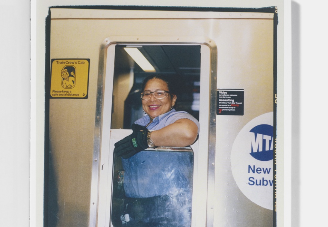 Smiling subway conductor looks out cab window.