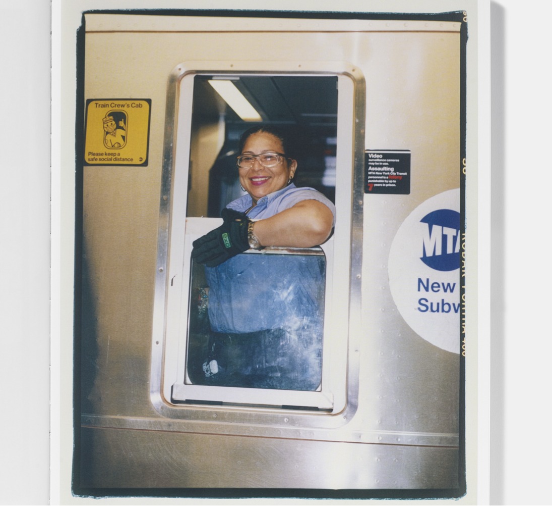 Smiling subway conductor looks out cab window.